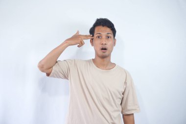 Sinirli genç adam kafasına silah hareketi yapıyor. Sıkıntıdan ya da sıkıntıdan kendini vuruyor. Beyaz arka planda duran aptalca bir şeyden bıkmış.