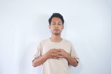 Young handsome man wearing cream t shirt over white background very happy and excited doing winner gesture with arms raised, smiling and screaming for success. Celebration