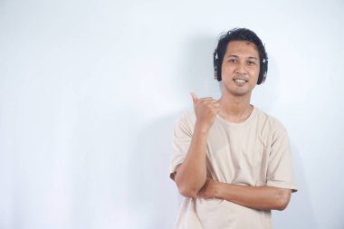 Asian man wearing headphones smiling amazed and surprised and pointing up with fingers and raised arms. isolated on white background
