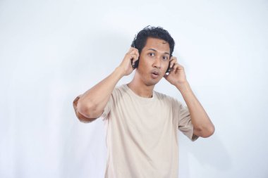 Asian man wearing headphones smiling in awe, surprised and liking the song playing