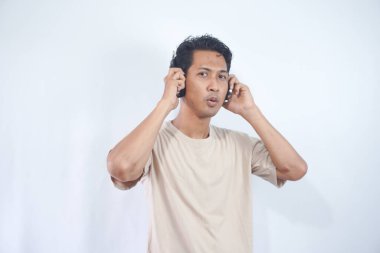 Asian man wearing headphones smiling in awe, surprised and liking the song playing