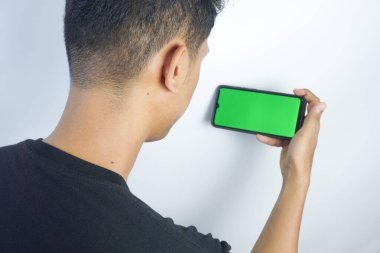 Close up shot of man holding a smartphone with chroma key mock up green screen - technology, connections, communications concept