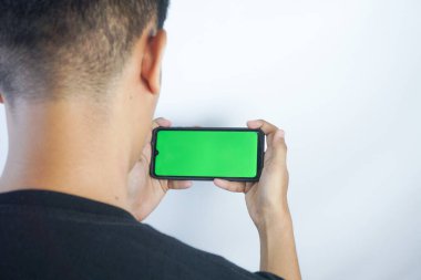 Close up shot of man holding a smartphone with chroma key mock up green screen - technology, connections, communications concept