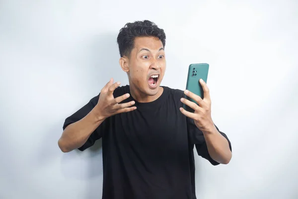 Smart Young Asian man is confused, angry and stresses when look smartphone in studio background.