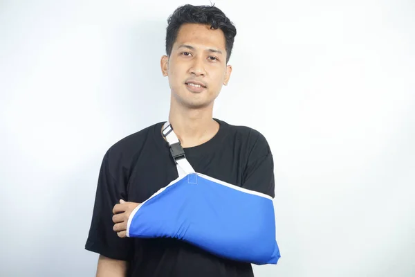 stock image Portrait of young man with hand injury wear splint for fast recovery. Injured male with cast or sling on shoulder, have arm or shoulder trauma. Rehabilitation and healthcare concept.