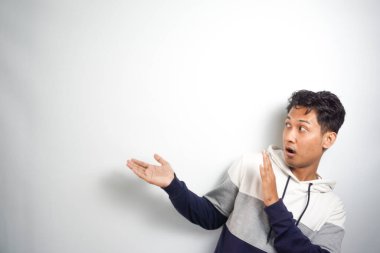 Yüzünde kocaman bir gülümseme olan sıradan bir kış kapüşonu giyen Asyalı yakışıklı adam kameraya el ve parmak ile bakıyor..