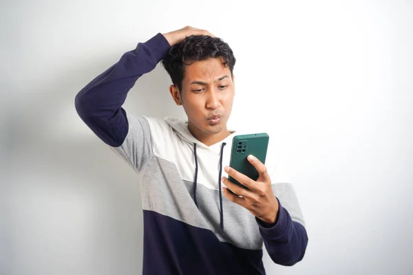 Smart Young Asian man is confused and stresses when look smartphone in studio background.