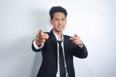 Adam işaret ediyor. Neşeli genç adam kamerayı doğrultuyor ve gülümsüyor.