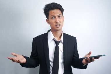 Asyalı bir adamın iki omuz silkip iki elini de kaldırdığı poz. Cehaletin örnekleri, neden olmasın, nerede ve ne yanlış. İzole edilmiş beyaz arka planda Endonezyalı bir adamın portresi