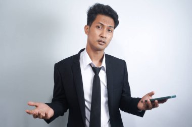 Asyalı bir adamın iki omuz silkip iki elini de kaldırdığı poz. Cehaletin örnekleri, neden olmasın, nerede ve ne yanlış. İzole edilmiş beyaz arka planda Endonezyalı bir adamın portresi