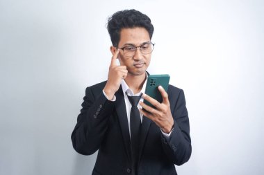 Yakışıklı genç yetişkin portresi, rüya gibi bakışlı, akıllı telefonu tutarken düşünen, beyaz arka planda izole edilmiş..