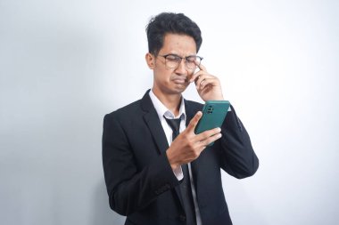 Asian guy wearing a suit looks sad reading online news from his cellphone. man shows disappointed gesture by wiping tears from his face