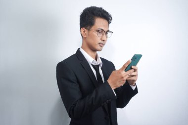 Photo of serious focused Asian man modern digital smart phone device, chats in social networks,