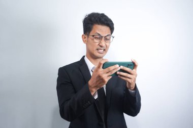 Takım elbiseli, tutkulu ve ciddi bir gencin portresi beyaz arka planda izole bir şekilde ofiste oyun oynuyor.