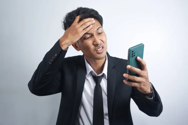 handsome young asian man wearing suit is angry and looking at cellphone
