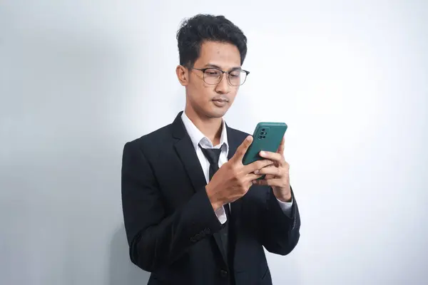 stock image Photo of serious focused Asian man modern digital smart phone device, chats in social networks,