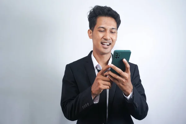 stock image Online Communication. Portrait Of Handsome Asian Businessman In Suit Holding Smartphone, Young Asian man Using Modern Device For Messaging Or Internet Browsing, Looking At Screen And Smiling