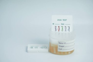 İdrar örneğini idrar kabına yerleştirip, uyuşturucu testinin bir kısmını idrara batırarak uyuşturucu içeriğinin incelenmesi. beyaz üzerine izole