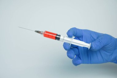 Beyaz arka planda izole edilmiş enjeksiyon için plastik şırınga tutan mavi eldivenli bir erkek. Sağlık, tedavi kavramı
