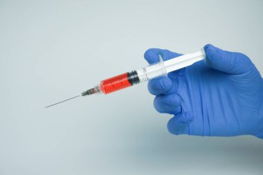 Beyaz arka planda izole edilmiş enjeksiyon için plastik şırınga tutan mavi eldivenli bir erkek. Sağlık, tedavi kavramı