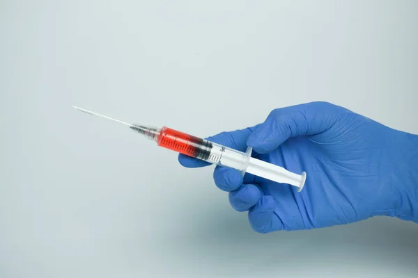 男性手戴蓝色手套 手持一个塑料塞环 内装液体 用于注射 在白色背景上隔离 治疗概念 — 图库照片