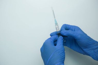 Beyaz arka planda izole edilmiş enjeksiyon için plastik şırınga tutan mavi eldivenli bir erkek. Sağlık, tedavi kavramı