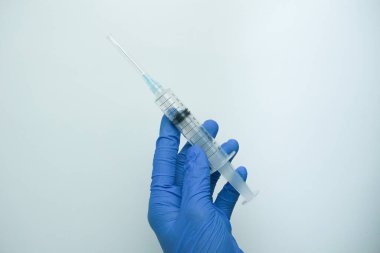 Beyaz arka planda izole edilmiş enjeksiyon için plastik şırınga tutan mavi eldivenli bir erkek. Sağlık, tedavi kavramı