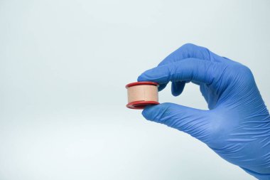 Tıbbi eldiven giyerken sıhhiye alçısını tutuyor. Sıvalar yaraların çarpmasını, zarar görmesini veya kirlenmesini önlemek için kullanışlıdır. Alçı genellikle bir örgü ile kaplıdır.