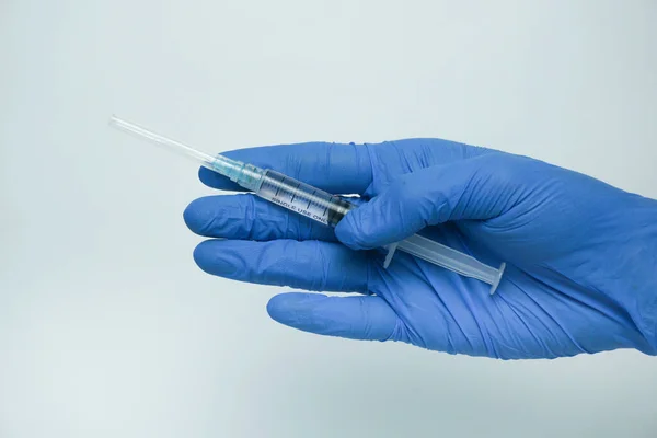 青い手袋の男性の手は白い背景に隔離された注射のための液体とプラスチック製のシリングを保持する 治療の概念 — ストック写真