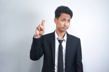 Genç Asyalı takım elbiseli ve parmakları çapraz