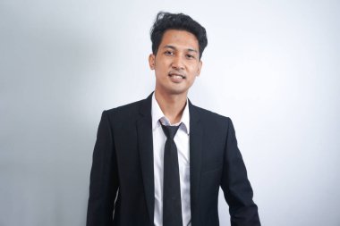 Resmi takım elbiseli yakışıklı Asyalı bir adamın portresi beyaz arka planda izole edilmiş dişlek bir gülümsemeyle kameraya bakıyor. Kendine güvenen işadamı, patron, serbest çalışan yönetici.