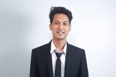 Resmi takım elbiseli yakışıklı Asyalı bir adamın portresi beyaz arka planda izole edilmiş dişlek bir gülümsemeyle kameraya bakıyor. Kendine güvenen işadamı, patron, serbest çalışan yönetici.