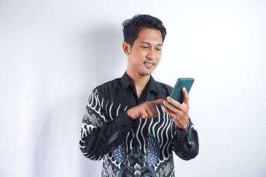 Beyaz arka planda izole edilmiş cep telefonu kullanan Batik tişörtlü gülümseyen genç adam görüntüsü