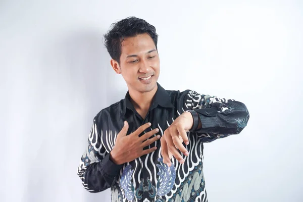 Happy and surprised Asian man who is looking at his watch. Shocked asian man in batik shirt looking at watch