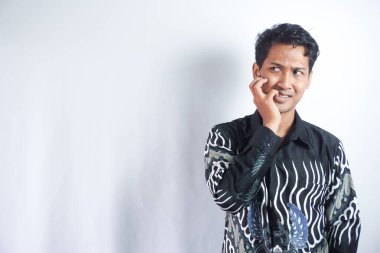 Batik tişört giyen yakışıklı Asyalı adam kaygı, korku ve endişelerini dile getiriyor.