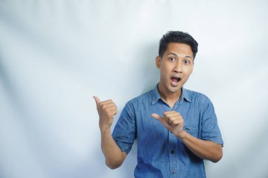 Omg, Cool Teklif. Asyalı genç bir adamın beyaz stüdyo arka planında izole edilmiş boş bir alanı göstermesine şaşırdım. Reklam metni veya reklam metni için yer ve mekan gösteren heyecanlı adam, afiş