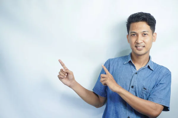 Unge Kjekk Asiatisk Mann Iført Blå Skjorte Isolert Bakgrunn Pekende – stockfoto