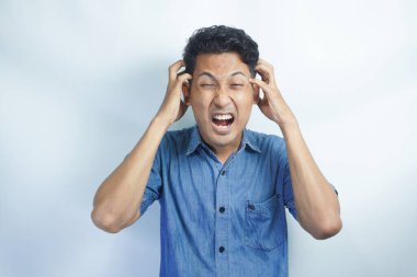 Yakışıklı delikanlı çünkü umutsuz ve stresli baş ağrısı acı izole arka plan üzerinde ağrı ve migren. Ellerini kafasına.