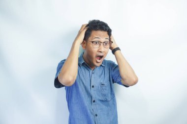 Şaşırmış / şaşırmış genç iş adamı el ele tutuşuyor ve ağzını açık tutuyor. Baş ağrısı ya da stres. İnsani duygular, yüz ifadeleri, duygu konsepti