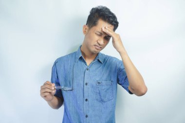 Yakışıklı delikanlı çünkü umutsuz ve stresli baş ağrısı acı izole arka plan üzerinde ağrı ve migren. Ellerini kafasına.