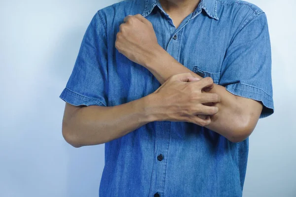 Man itching and scratching his arm from allergy symptoms on white background, health and medical care concept.