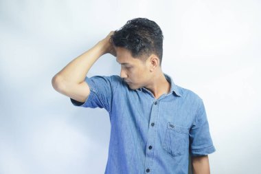 Bir adam koltuk altının kokusunu gömleğinden alır. Koltukaltında vücut kokusu var mı diye bakıyorum. Terleme önleyicisi işe yarıyor. Beyaz bir arkaplanda izole edilmiş.