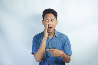 Beyaz arka planda mavi gömlekli genç bir adam. Ağız üstünde el ele. Gizli dedikodular, kötü niyetli konuşmalar.