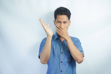 Ne iğrenç bir koku. Hoşnutsuz komik adamın portresi, burnu parmaklarla kaplayan ve hoşnutsuzluktan kaşlarını çatan. Pis koku ya da osuruk kokusu