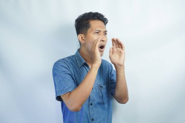 Yakışıklı delikanlı bağırarak ve ağzı üzerinde el ile yan için çığlık izole arka plan üzerinde. İletişim kavramı.