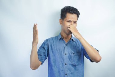 Ne iğrenç bir koku. Hoşnutsuz komik adamın portresi, burnu parmaklarla kaplayan ve hoşnutsuzluktan kaşlarını çatan. Pis koku ya da osuruk kokusu