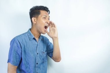 Yakışıklı delikanlı bağırarak ve ağzı üzerinde el ile yan için çığlık izole arka plan üzerinde. İletişim kavramı.