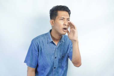 Yakışıklı delikanlı bağırarak ve ağzı üzerinde el ile yan için çığlık izole arka plan üzerinde. İletişim kavramı.