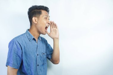 Yakışıklı delikanlı bağırarak ve ağzı üzerinde el ile yan için çığlık izole arka plan üzerinde. İletişim kavramı.