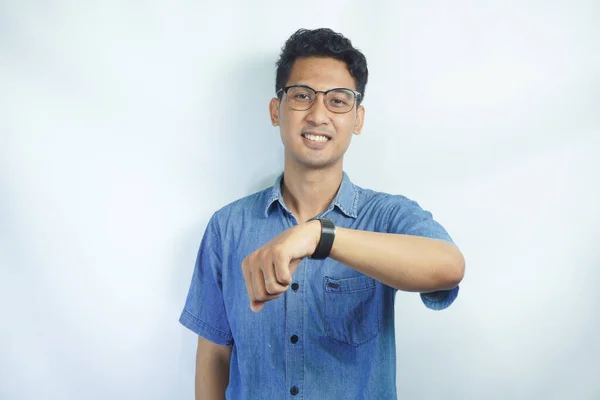 一个身穿蓝色衬衫的亚洲男人面带微笑地看着他的白底手表的画像 — 图库照片